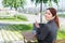 Smilling caucasian woman sits at a wooden table on a summer terrace and uses a smartphone