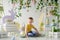 Smilling child sits on wooden floor in Easter studio decoration with flowers, wooden rabbits, eggs