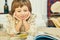 Smilling little Caucasian girl lying on the floor and reading an illustrated book.