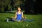 Smilling young woman sitting in lotus position on yoga mat in pa