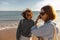 Smilng couple in love fool around while walking along the beach on sunny windy day