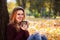 Smilng girl with cup of tea in the autumn park