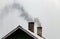 Smoke billows from the house`s chimneys. Furnace heating of the house.