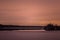 Smoke factory river trees. shoreline and trees on it. Trees are seen silhouetted against the sunset sky