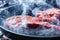 Smoke and steam rise from a beaf steak on grill pan