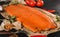 Smoked fillet salmon, red fish steak with spices and lemon on craft paper over dark stone background. Tenderloin fish still life,