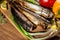 Smoked fish mackerel on wooden cutting board on background of vegetables pepper, tomato, green onions