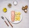 Smoked fish, with potatoes and dill on a white plate, with spices, knife and fork wooden rustic background top view close up