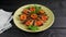 Smoked fishes of sprats without their heads with sliced tomatoes, parsley and spices in a  plate on a  table