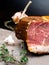 Smoked ham on a stone table with addition of fresh aromatic herbs and spices. Natural product from organic farm, produced by
