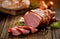 Smoked meat, Sliced smoked gammon on a wooden table with addition of fresh herbs and aromatic spices.
