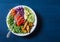 Smoked salmon, baked potatoes, vegetables buddha power bowl on blue background, top view. Red cabbage, carrots, arugula, potatoes,