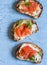 Smoked salmon and cream cheese sandwich. On a blue background, top view. Delicious appetizers with wine