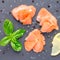 Smoked salmon filet with lemon and basil on gray stone, top view, square format