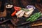 Smoked Sardine fish fillet on wooden board with herbs. Dark wooden background. Top view