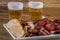 Smoked sausage with bread and onions and glasses of beer on wood background. Snack appetizer calabrese sausage with onion