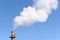 Smokestack billowing a large cloud of steam against a blue sky, horizontal format