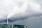 A smokestack emitting white fumes against a stormy sky