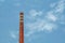 Smokestack in shape of wine bottle neck with text In vino veritas. Industrial chimney on cloud sky background with copy space.