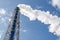 Smokestack and steam on blue sky background