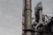 Smokestacks, ladders,and walkways of steel mill against gray sky, copy space