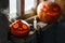 Smoking Halloween pumpkins on the dirty window sill of an old house window. Big spooky helloween symbol. Selective focus