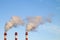 Smoking industrial stacks in a thermal power plant emit polluted air into the atmosphere in the blue sky