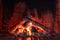 Smoldering logs and embers in a clay brick fireplace in a country cottage