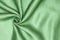 Smooth elegant green silk or satin luxury cloth texture can be used as abstract background. Crumpled fabric Twisted at the side