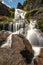 Smooth flowing waterfall cascading down rocks with vibrant green moss growing on them