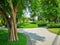 Smooth green grass lawn, greenery trees and shrub in a good maintenance landscape and garden, gray curve pattern walkway