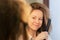 Smooth hair, curly woman straightens it with an iron in the bathroom, beauty and hairstyle