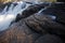 Smooth milky white waterfall on dark-colored rocks - side view- Long exposure