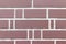 Smooth red decorative brick wall with white cement grout between them. Brick fence background texture