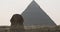 Smooth transition from the Sphinx to the Great Pyramid of Giza in Cairo, Egypt. Clear day, tourists in the background