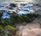 Smooth waves gently wash over rocks at a beach in Kauai Hawaii