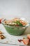 Smoothie bowl with banana and spirulina, almond flakes, chia seeds, pumpkin seeds and strawberry on white background