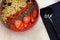 Smoothie bowl with blend fruits, strawberry, goji, chia seeds, and green buckwheat granola, and metal black spoon, on the table