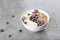 Smoothie bowl with granola, raspberries, blueberries and bananas on grey background. Delicious Breakfast with muesli