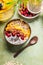Smoothie bowl with mango and tropical fruits , chia seeds yogurt pudding and cranberries, nuts, oatmeal topping in coconut shells