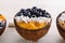 Smoothie bowls with blueberries, frozen mango puree and coconut shavings in coconut bowl on white background