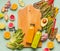 Smoothie making concept. Various healthy fresh fruits and vegetables with bottles on light mint table background with cutting boar