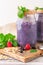 Smoothies with blueberries, raspberries, black currants and mint. In the original glass jars. Embossed wooden table. White washed