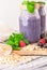 Smoothies with blueberries, raspberries, black currants and mint. In the original glass jars. Embossed wooden table. White washed