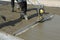 Smoothing fresh concrete with gas powered vibrating screed machine