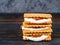 Smores, marshmallow sandwiches - traditional American sweet chocolate cookies on dark wooden table, side view