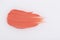 Smudged pink orange lipstick on white background