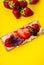 Snack with crispbread, cream cheese, fresh strawberry and basil on a yellow background