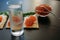 Snack with red caviar and glass of cold vodka on black wooden background. Spirits and traditional starter