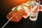 Snack with red caviar and glass of cold vodka on black wooden background. Spirits and traditional starter